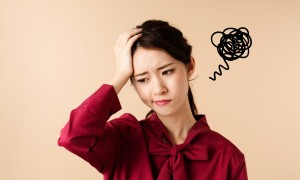 頭を抱えて困っている女性のイメージ