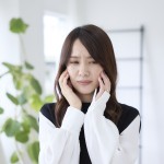 歯が痛くて頬を押さえる女性