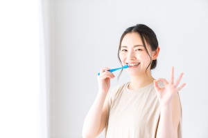 歯磨きをしながらOKマークをする女性