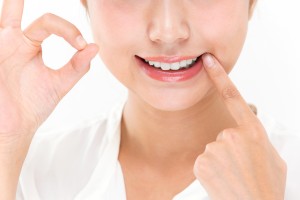 自身の歯を指さしてOKマークをする女性