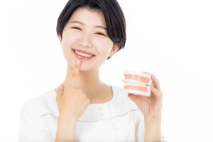 自身の歯を指さして微笑む歯科衛生士のイメージ