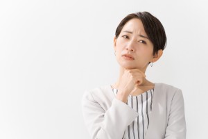 顎に手を当てて首を傾げる女性
