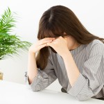 頭を抱えて考え込む女性