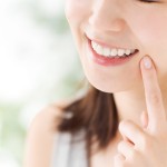 歯を指さして微笑む女性