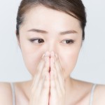 口を手で隠す女
