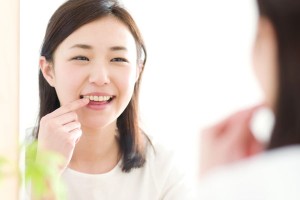 鏡で前歯を見る女性