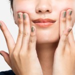 手で口角を上げようとする女性