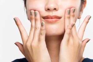 手で口角を上げようとする女性