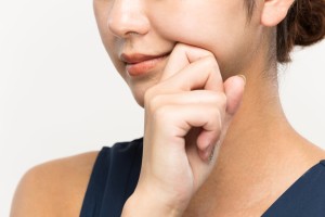 口角を手で触れる女性のイメージ