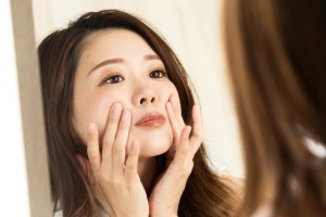 鏡で顔を見る女性のイメージ